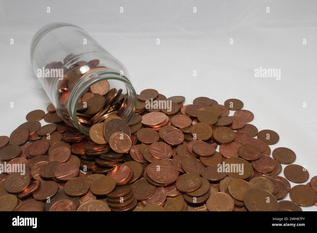British one and two pence coins falling out of a saving jar Stock Photo
