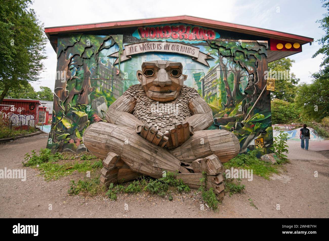 Wooden statue of giant troll Green George (by Thomas Dambo) and painted wall in  Christiania free town district (founded in 1971), Copenhagen, Denmark Stock Photo