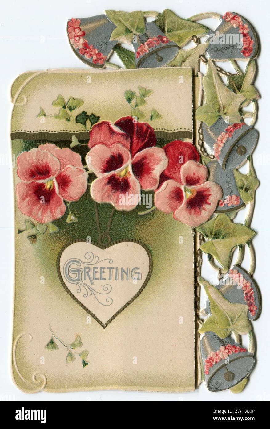 An antique Victorian Valentine’s Day greetings card depicting flowers, bells and ivy with the word “Greeting” within a heart-shaped pendant. Stock Photo