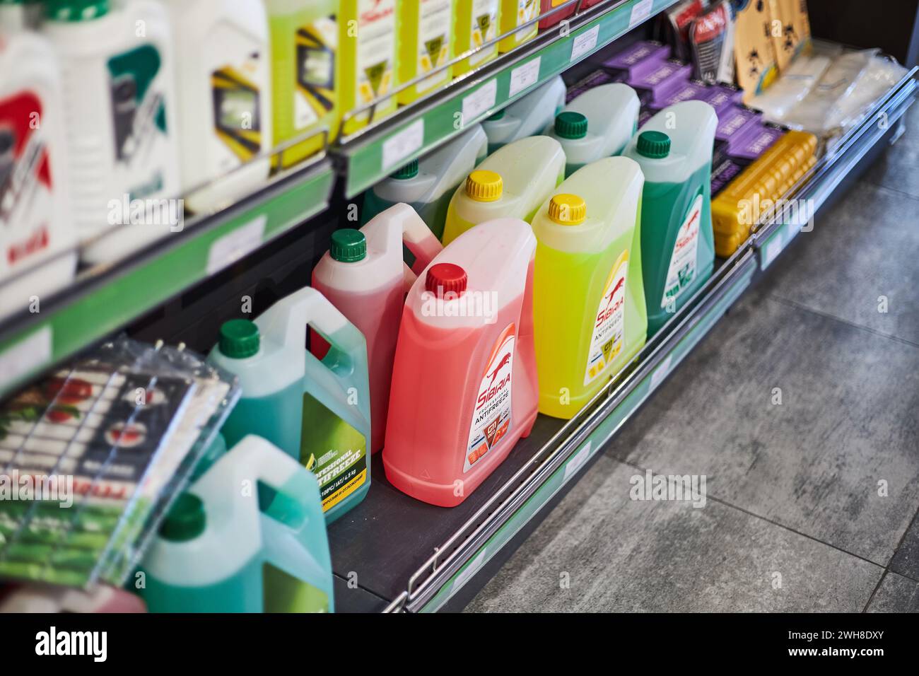 Showcase with automotive products at gas station store. Plastic cans with antifreeze in different colors: pink, yellow, green. Automobile goods for ca Stock Photo