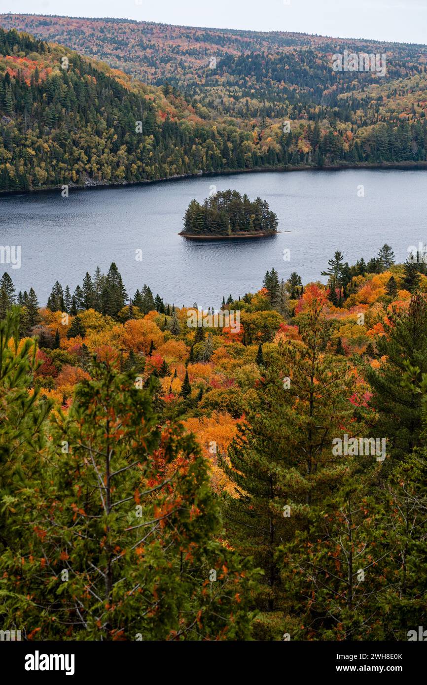 Pine Island in the middle of Wapizagonke lake surrounded by colorful forested hills in Autumn, La Mauricie National Park, Quebec, Canada Stock Photo