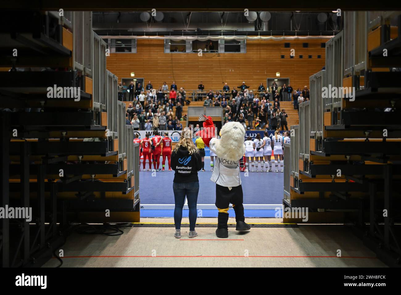 Berlin, Germany. 08th Feb, 2024. Hockey/Hall, Women: European Championship, Germany - Turkey, preliminary round, group A, match day 2. Schlenzi, mascot of the German national field hockey teams, stands between two stands with a volunteer. Credit: Sebastian Christoph Gollnow/dpa/Alamy Live News Stock Photo