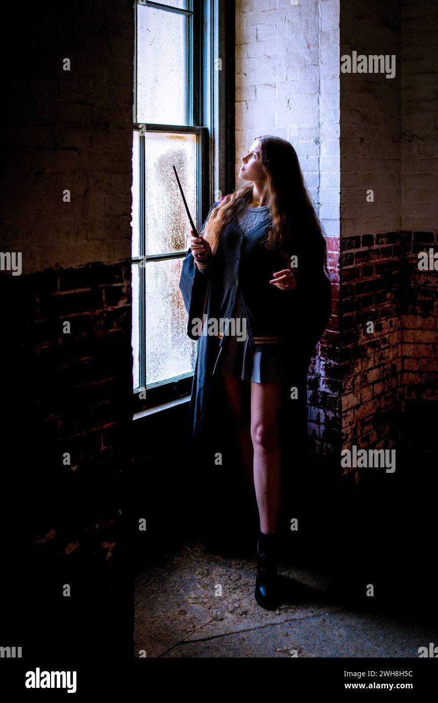 Young Woman Standing by a Window Harry Potter Style Witches Robes and Wand Moody Room for Copy Space Stock Photo