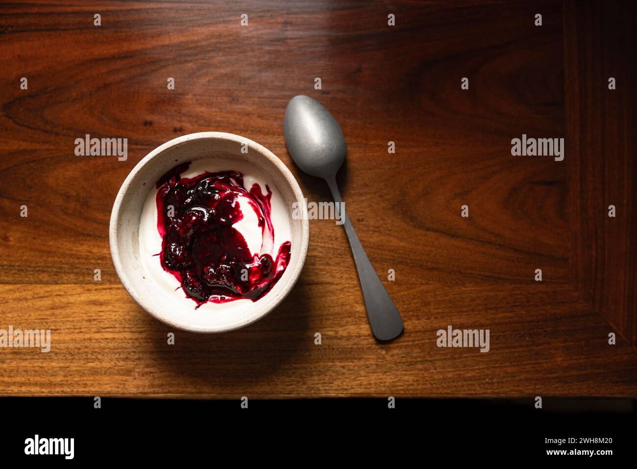 Bowl of yoghurt and blackberry compot on antinque wooden table with silver spoon. Stock Photo