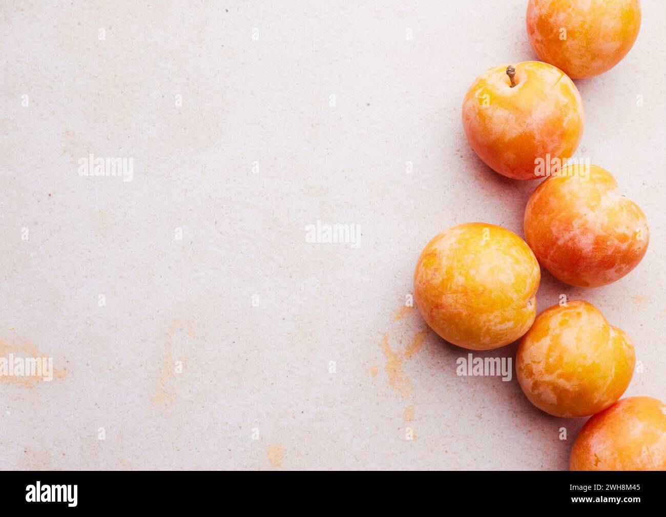 Yellow plums on a light pink background Stock Photo