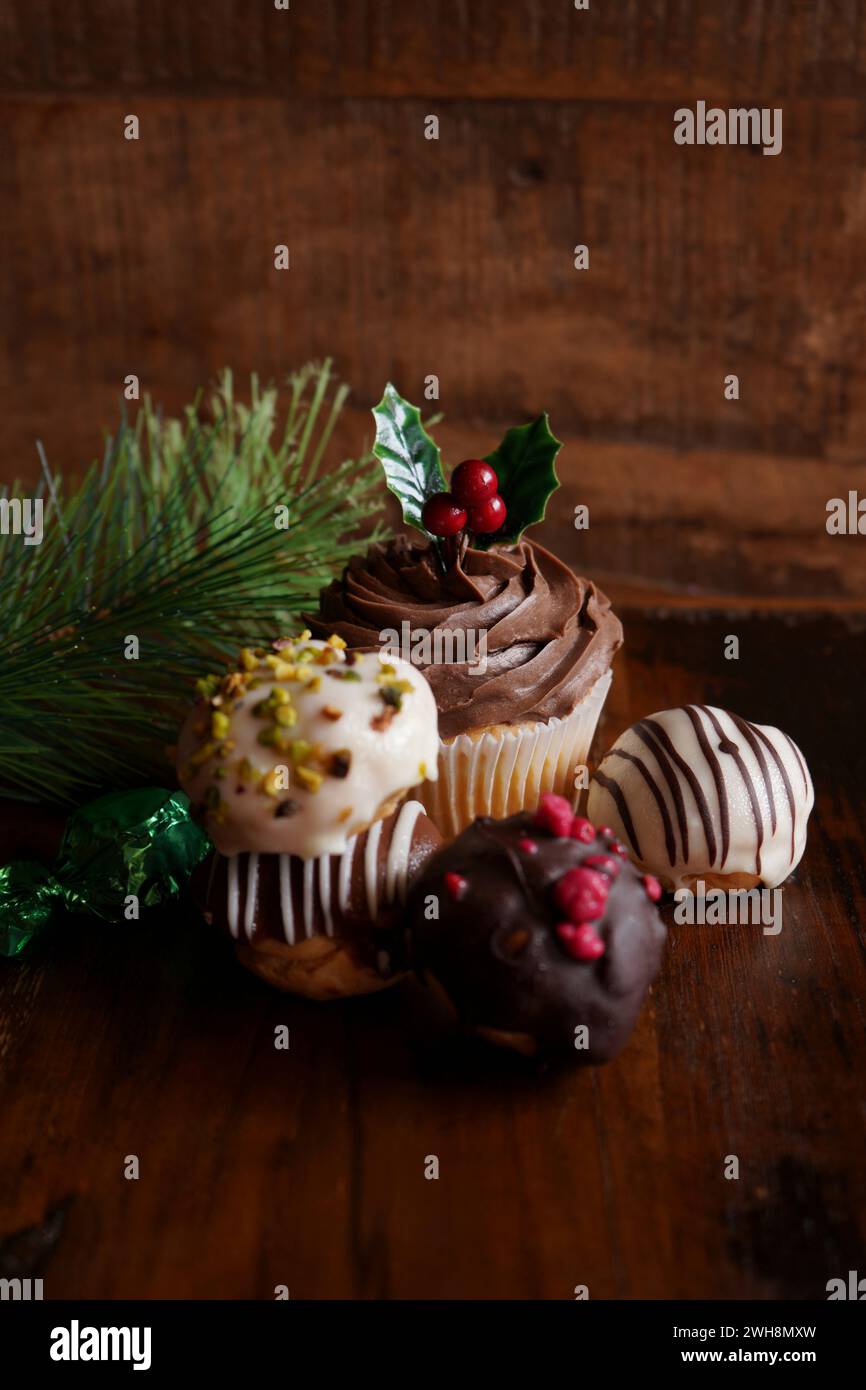 Christmas holiday chocolate cupcake and profiteroles treats against a dark wood background, with copy space. Stock Photo