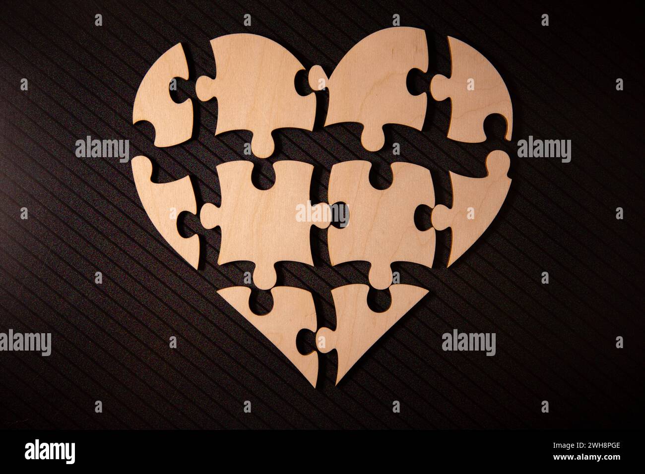 Shape of heart made from cardboard puzzles. Valentines Day background with heart from jigsaw puzzle parts on white background. Stock Photo