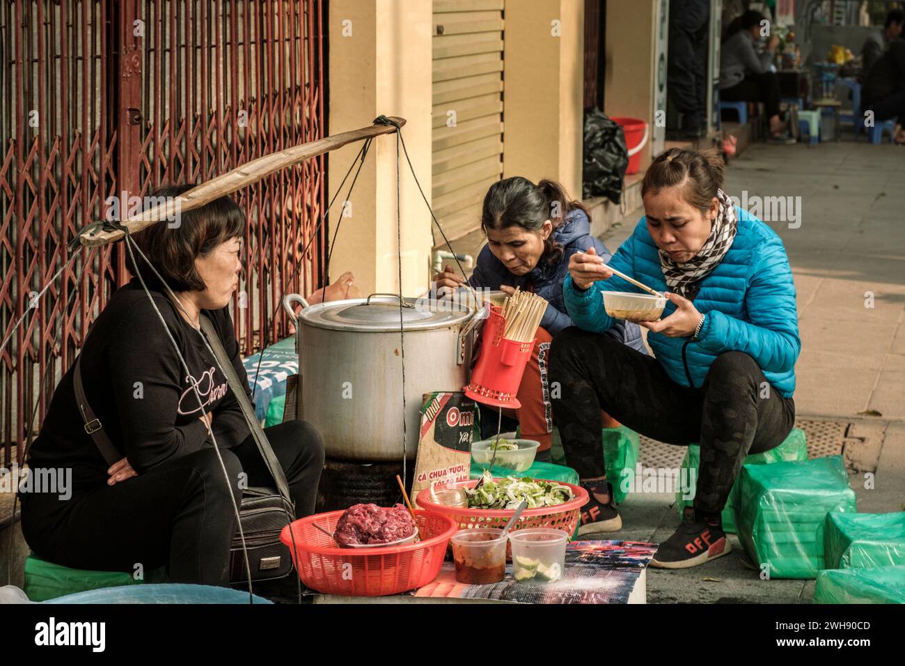 Customers enjoy a fresh bowl of pho from an impromptu street seller in Hanoi, Vietnam Stock Photo