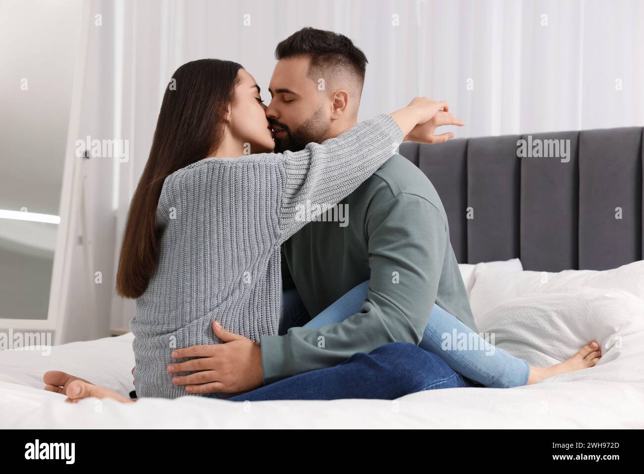 Cute relationship. Affectionate young couple kissing in bedroom Stock Photo