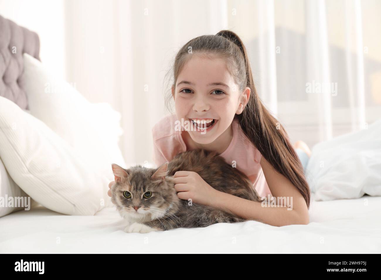 Cute little girl with cat lying on bed at home. First pet Stock Photo ...