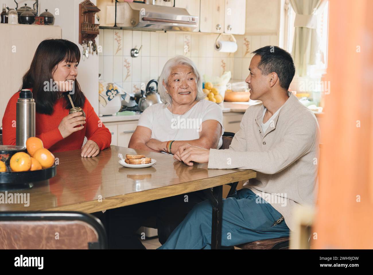 Japanese Family talking and drinking yerba mate at home. Argentinian family of Japanese descent sharing mate at home. Stock Photo