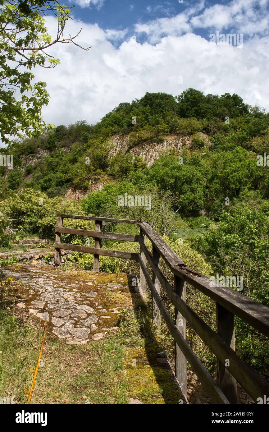 Wooden rail on a walking path near a castle ruin with a cliff on Rotenfels in the background on a sunny spring day in Rhineland Palatinate, Germany. Stock Photo