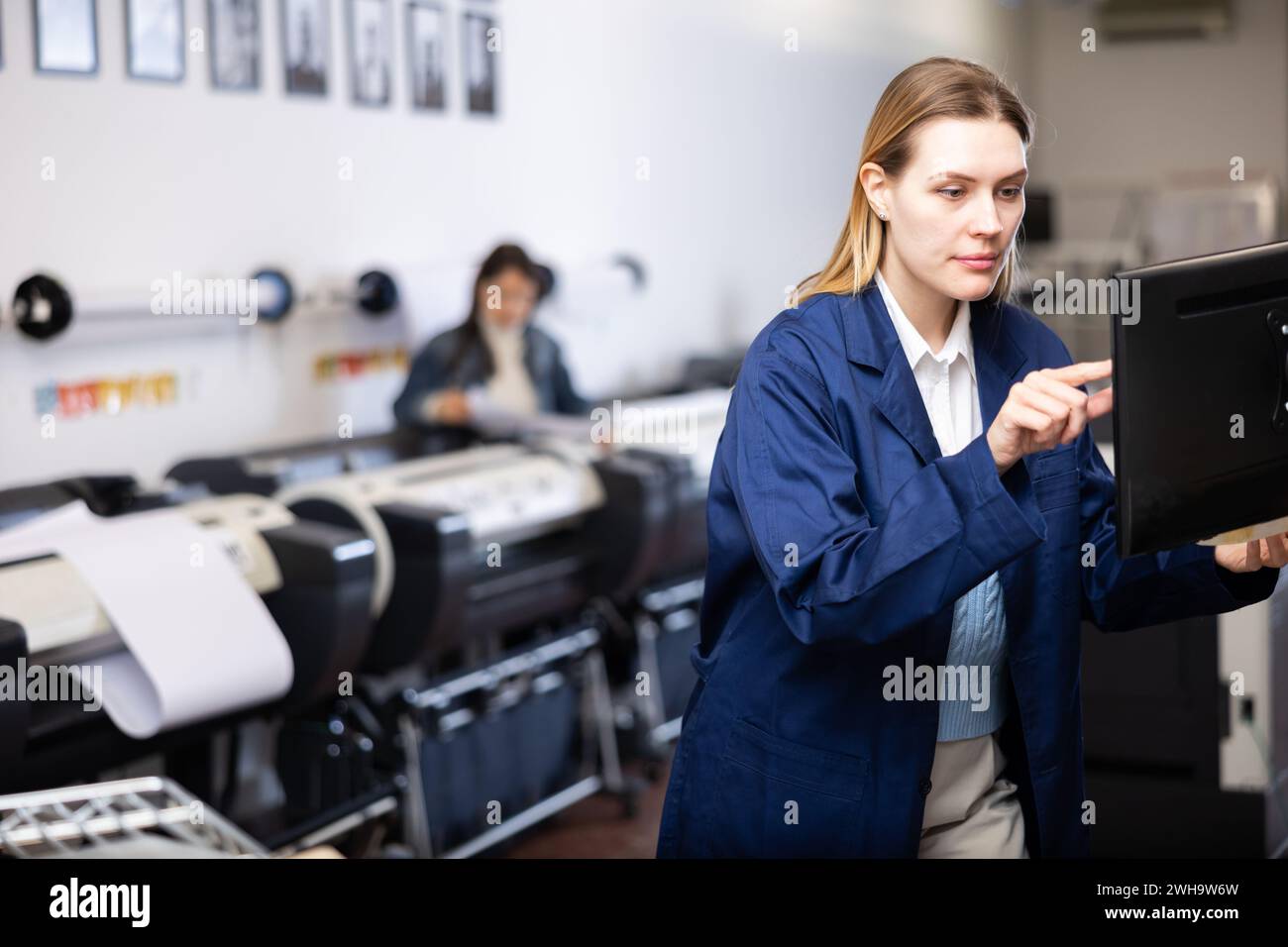 Technician operator calibrating plotter machine, typing on computer keyboard Stock Photo