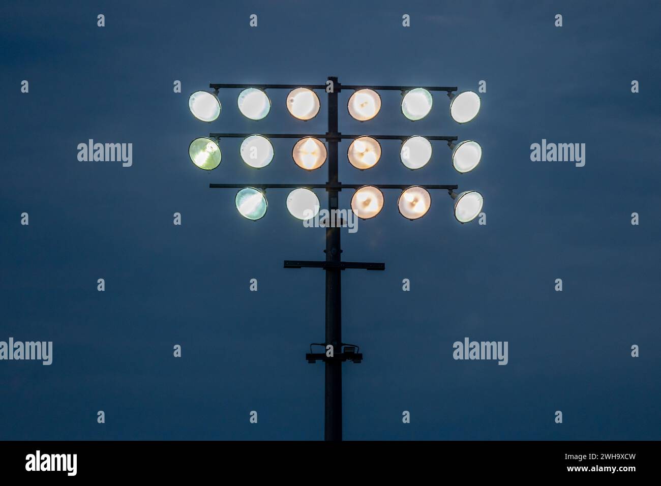 Abstract view of illuminated outdoor stadium lights against a darkened sky at dusk Stock Photo