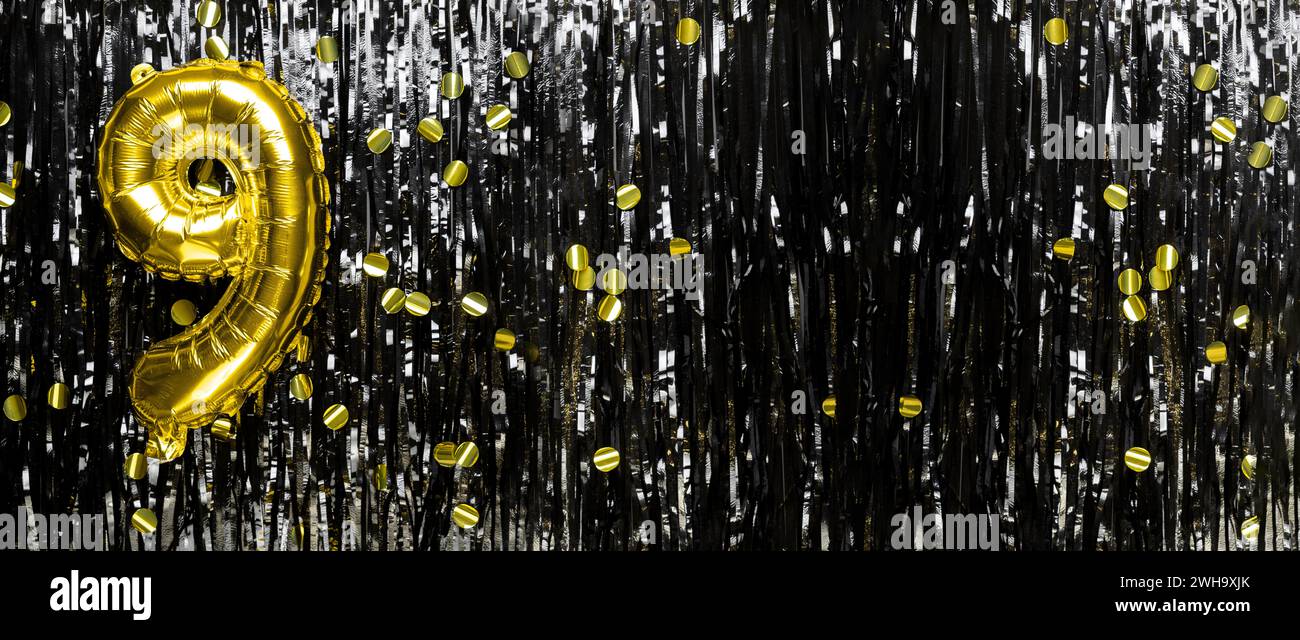 Gold foil balloon number number 9 on a background of black tinsel