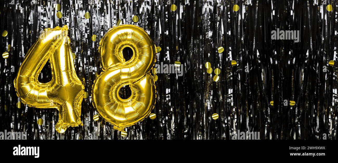 Gold foil balloon number number 48 on a background of black tinsel decoration. Birthday card, inscription forty-eight. Anniversary event. Banner. Stock Photo