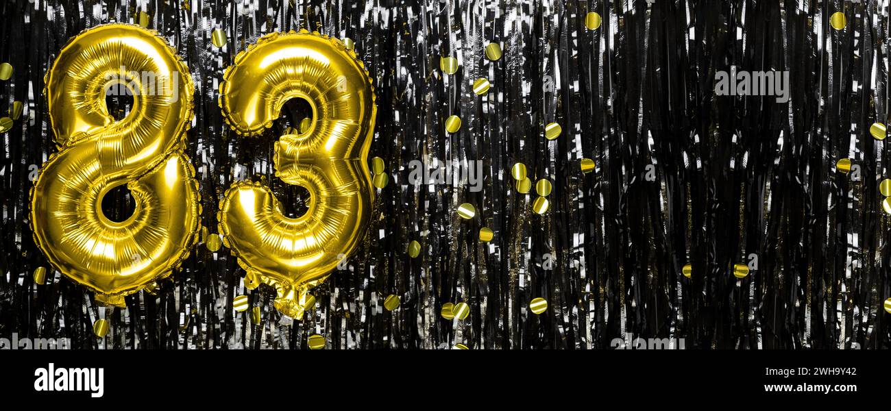 Gold foil balloon number number 83 on a background of black tinsel decoration. Birthday greeting card, inscription eighty-three. Anniversary event Stock Photo