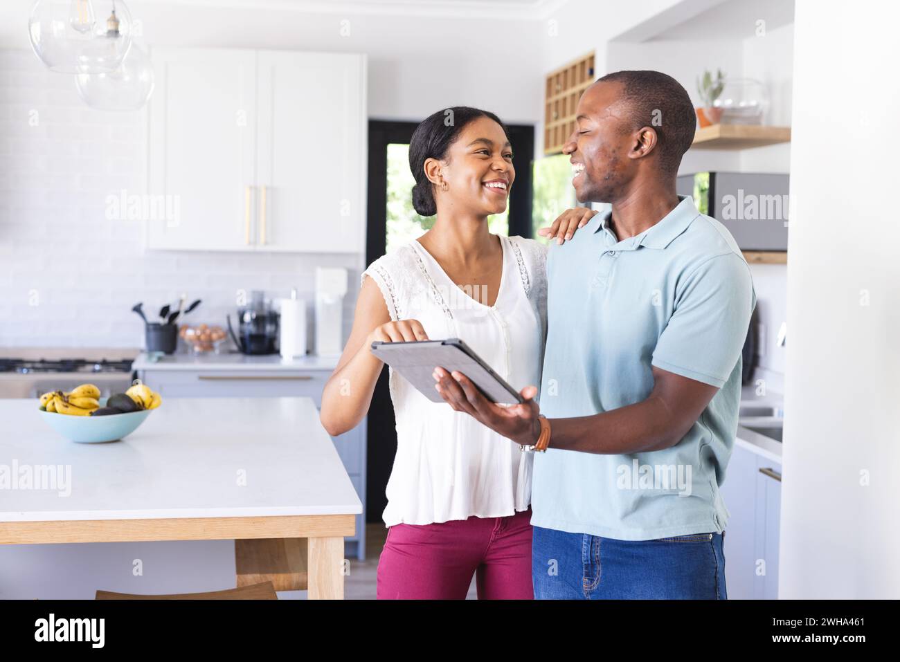 Biracial woman and African American man share a moment in the kitchen Stock Photo