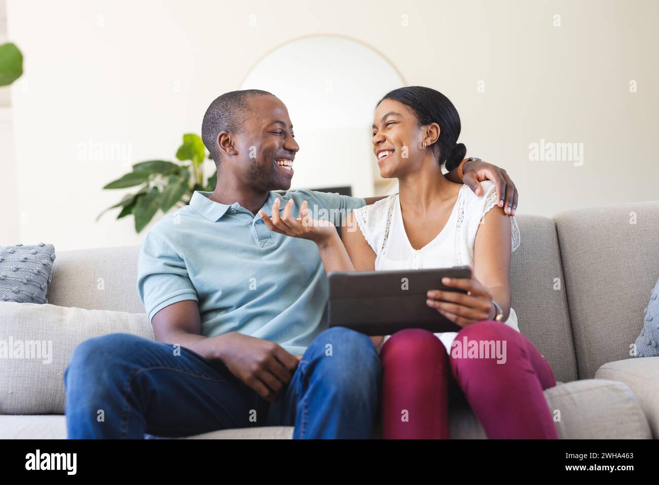 Young biracial woman and African American man share a tablet at home Stock Photo
