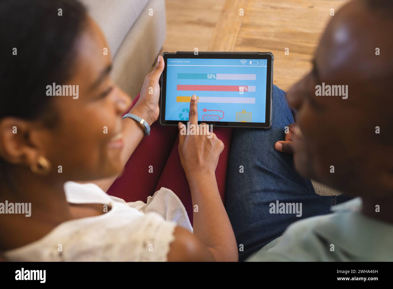 African American couple reviews finances and manages their smart home app on a tablet at home Stock Photo