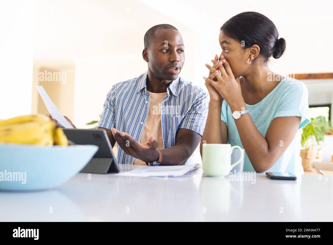 Couple discusses finances in a bright kitchen. Stock Photo