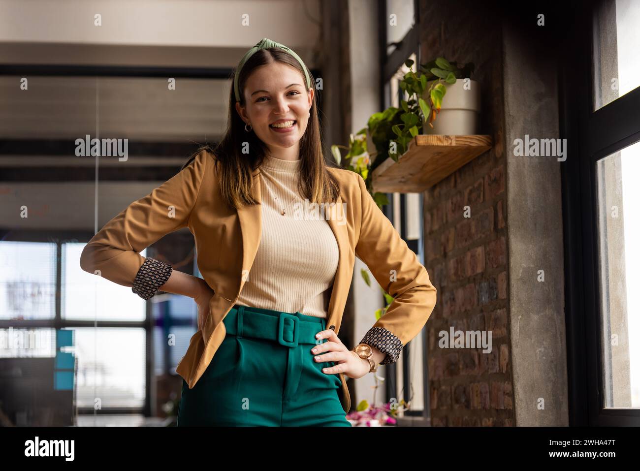 Young Caucasian woman poses confidently in a casual business setting in a modern office Stock Photo