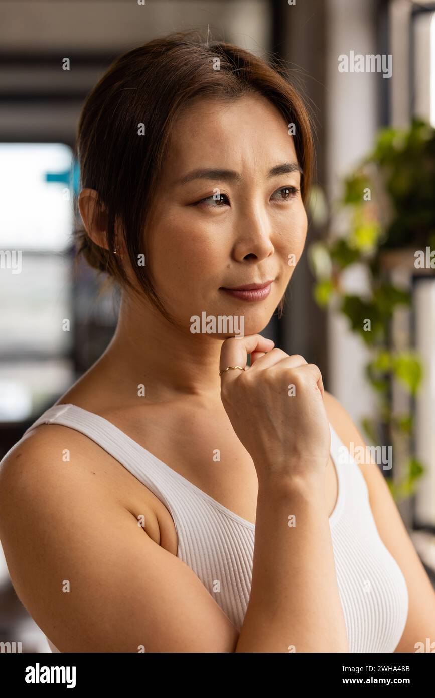 Asian woman appears contemplative in a casual business office setting Stock Photo