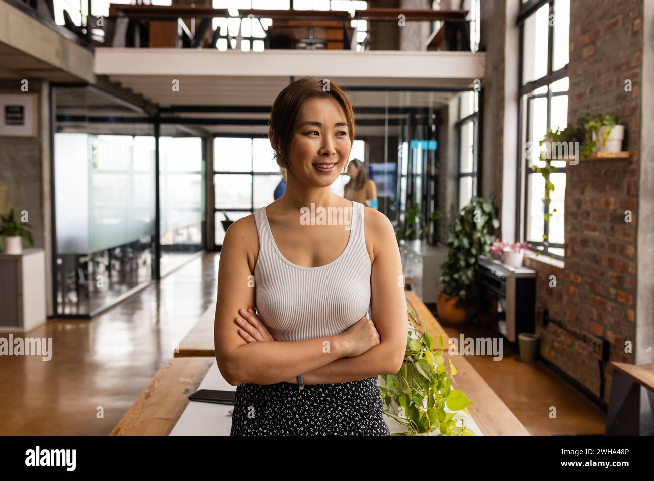 Confident Asian woman stands in a modern office, exuding casual business professionalism Stock Photo