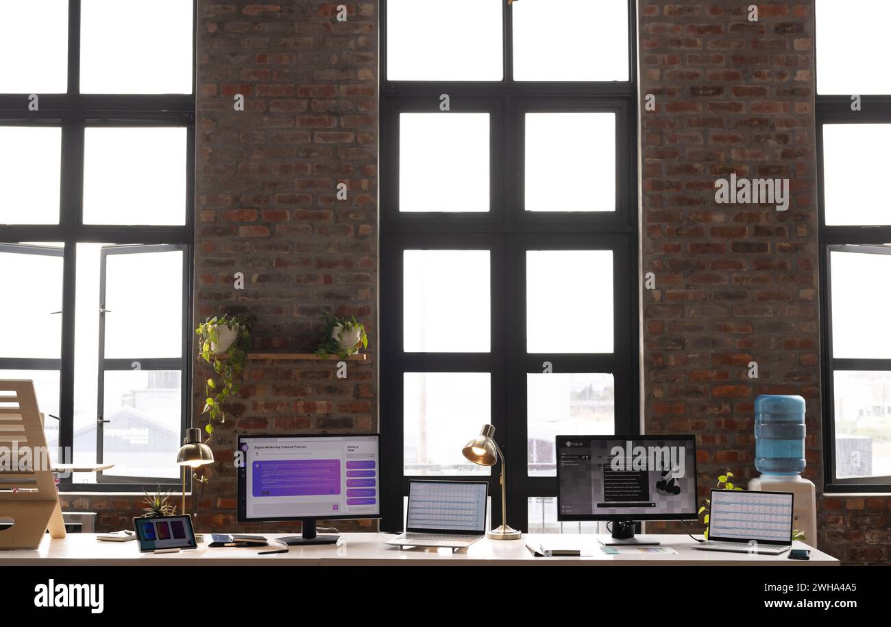 A modern casual business office setup with large windows and multiple monitors Stock Photo