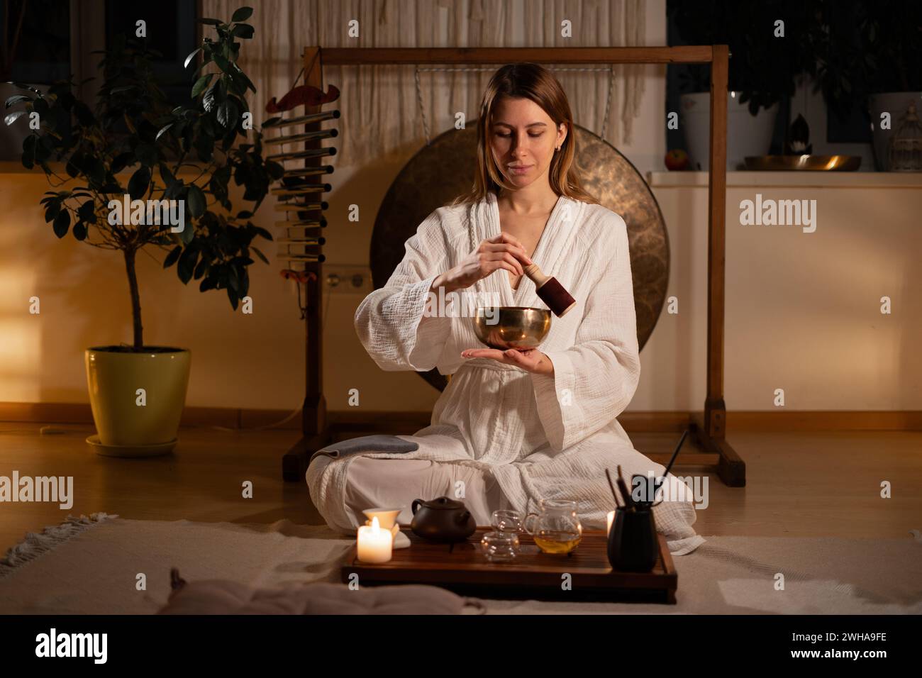 Traditional chinese ceremony. Woman performs the sacrament of an oriental tea ceremony at home for her husband and uses singing Tibetan bowl for relax Stock Photo