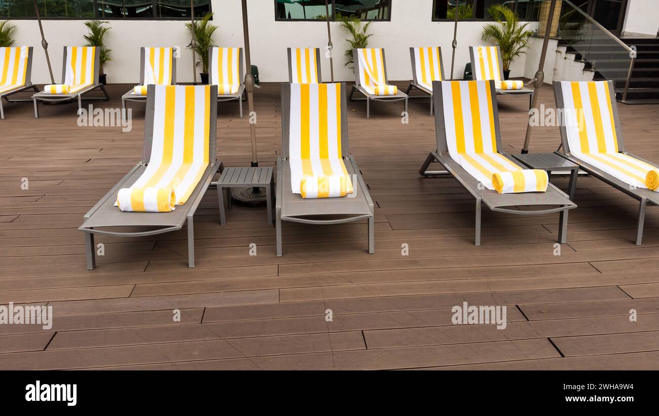 Pool chairs or sun loungers arranged neatly on a pool deck. Stock Photo