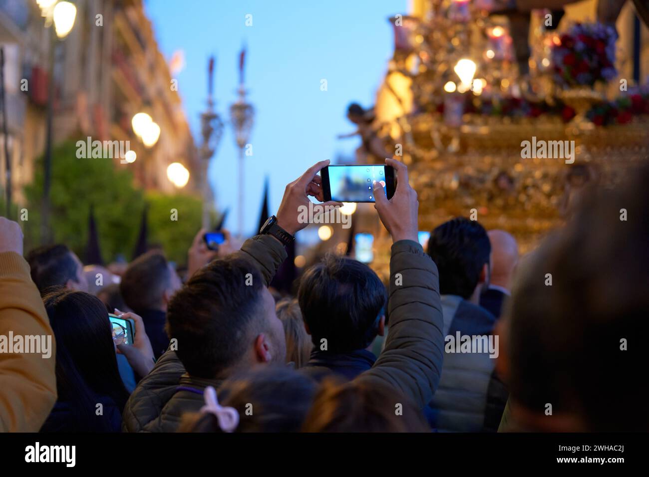 In the predawn hours of Maundy Thursday in Seville, Spain, devout worshipers gather along the streets to witness the solemn beauty of the Holy Week pr Stock Photo