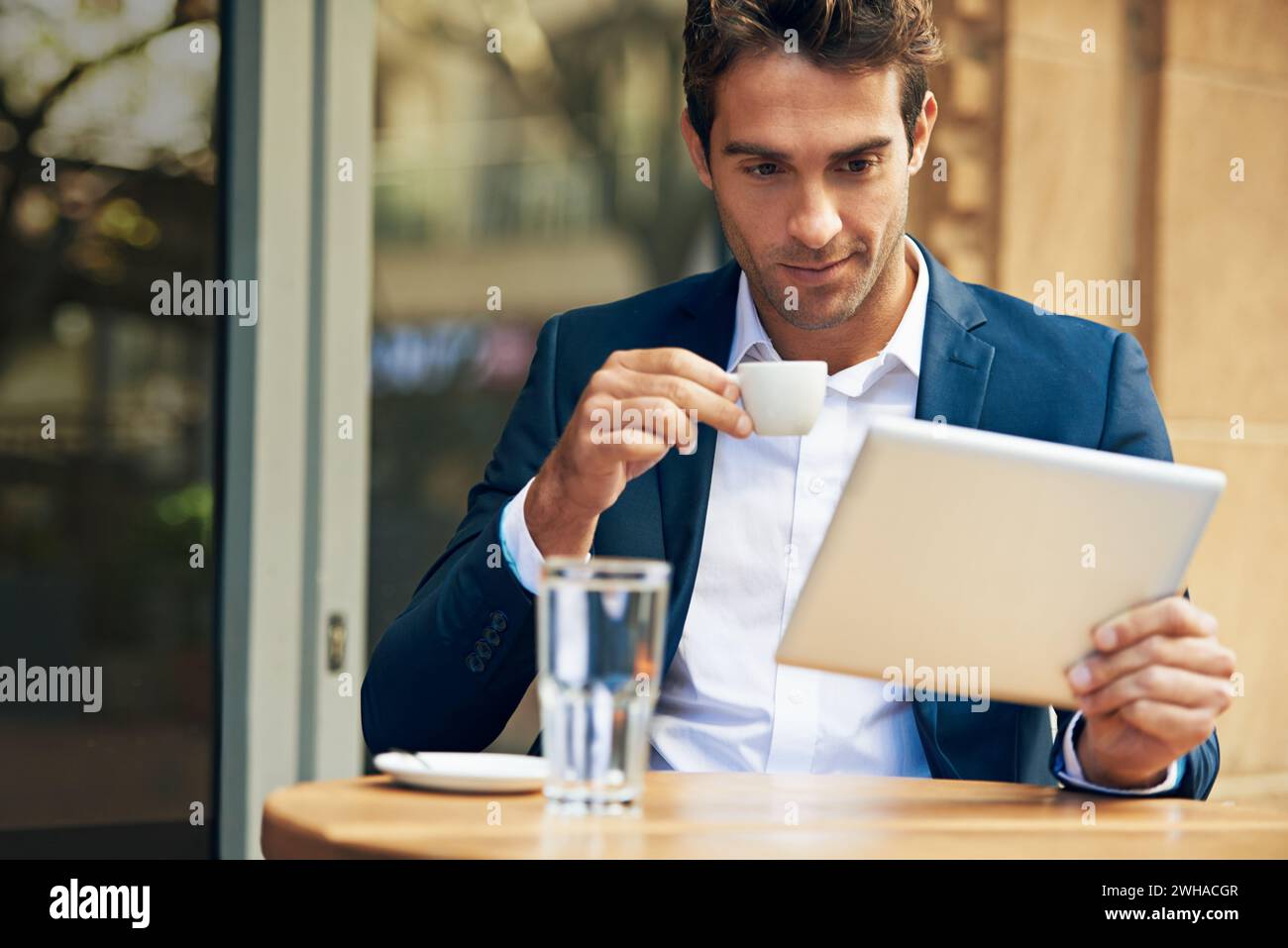 Businessman, reading and outdoor at cafe with tablet for news, article or internet research in London. Online, communication and drink espresso with Stock Photo