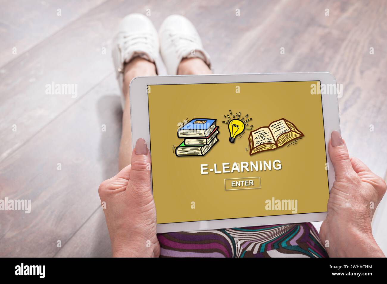 Woman sitting on the floor with a tablet showing e-learning concept Stock Photo