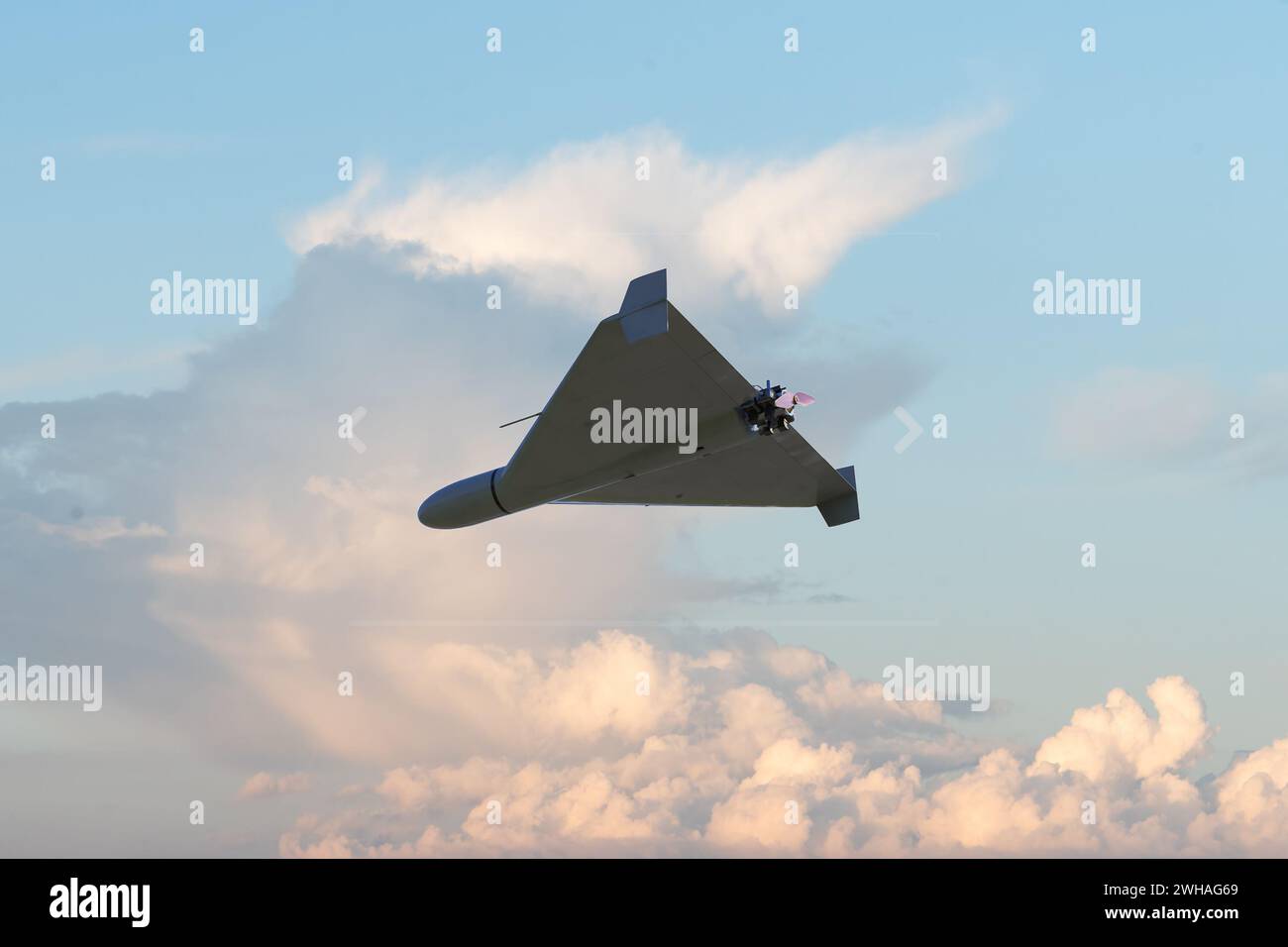 A kamikaze combat drone flies against the sky and clouds, UAV attack and targeting, war in Ukraine and Russia. Stock Photo