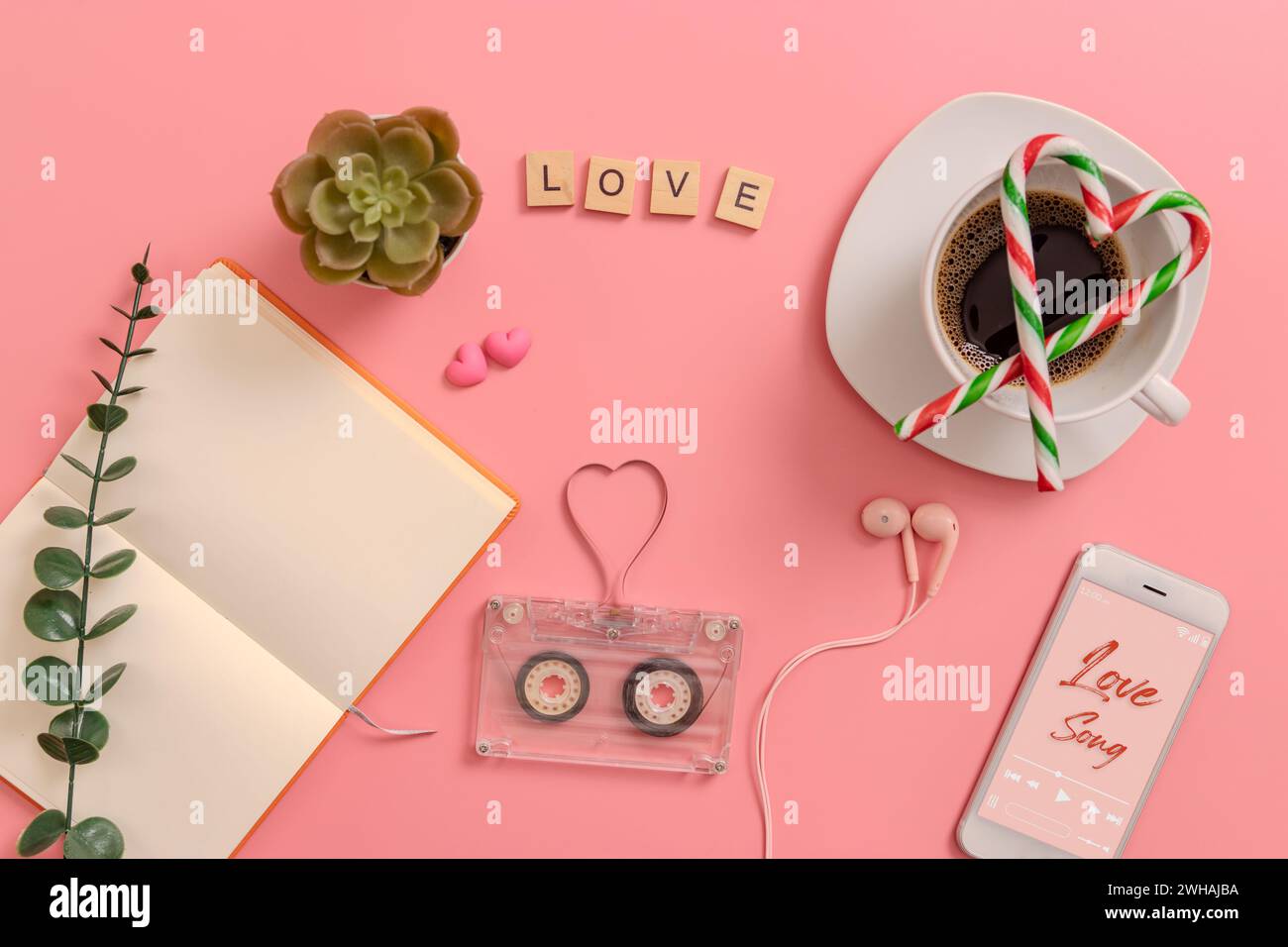 vintage transparent audio cassette magnetic tape in shape of heart, open blank book page, candy cane in the shape of heart on coffee cup, earphones, c Stock Photo