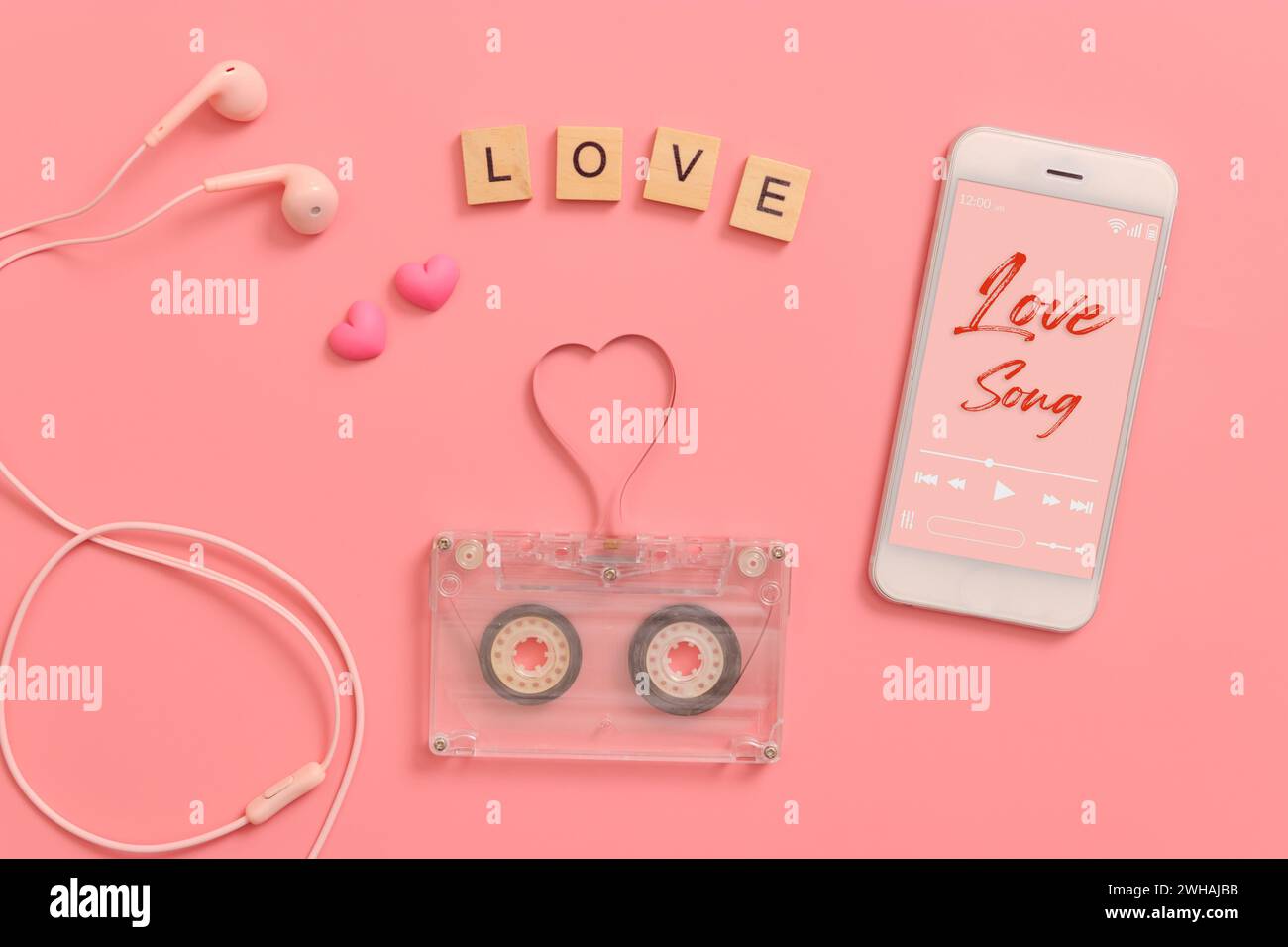 vintage transparent audio cassette magnetic tape in shape of heart, earphones, mobile phone playing love song on screen. flat lay Valentine's Day musi Stock Photo