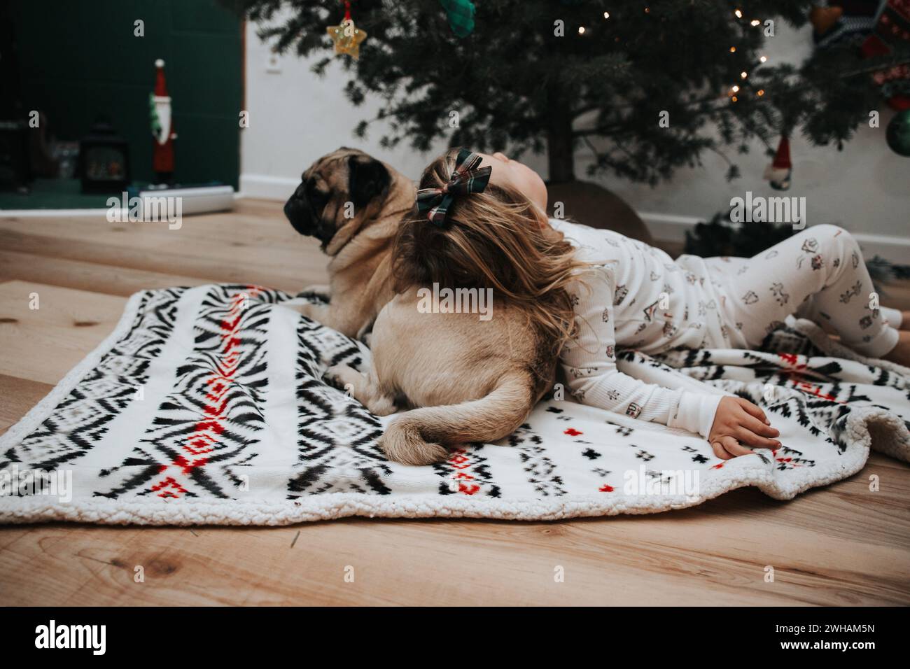 Cute girl in christmas pajamas with pug pillow Stock Photo