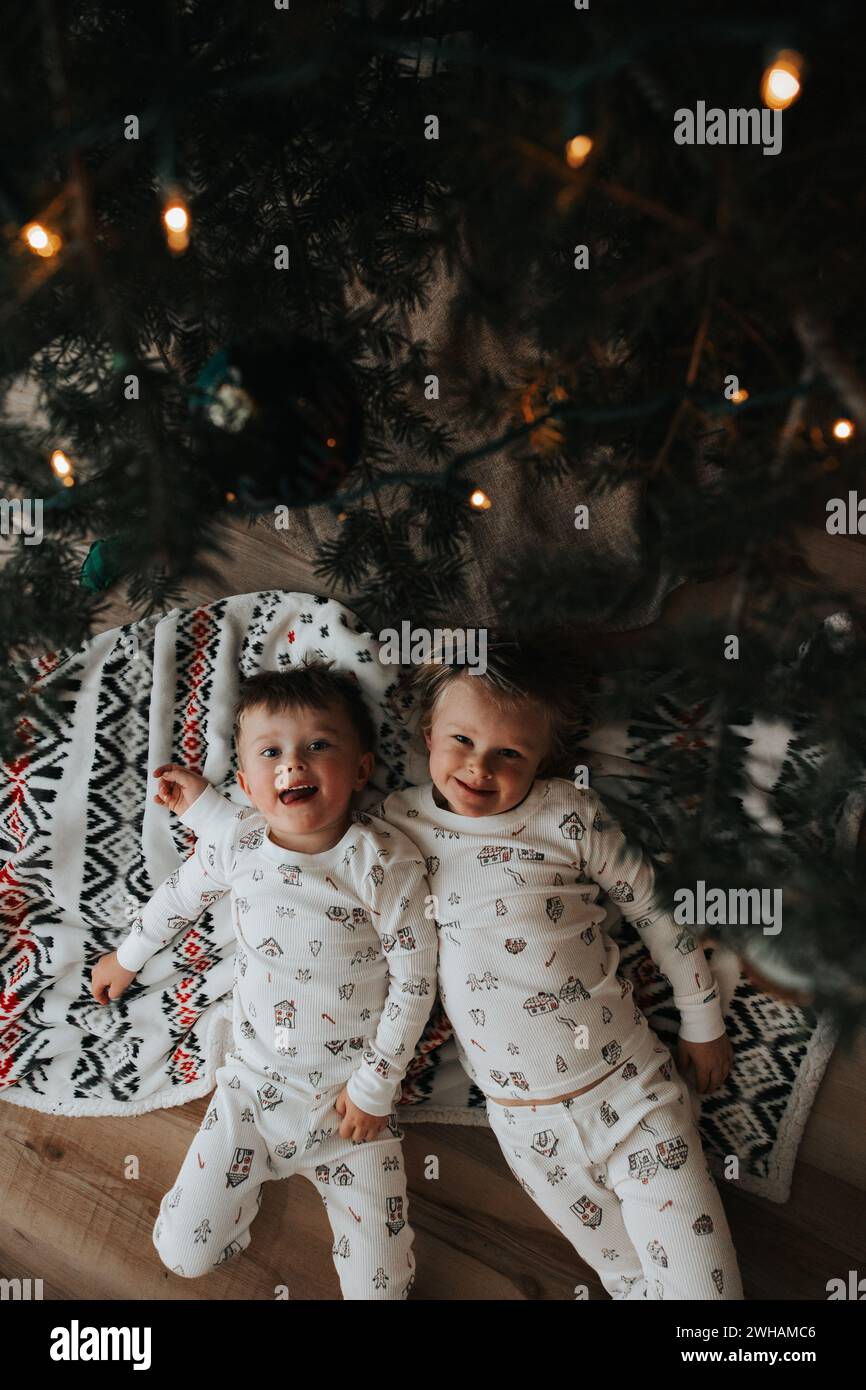 Siblings lay under tree, christmas comfort Stock Photo