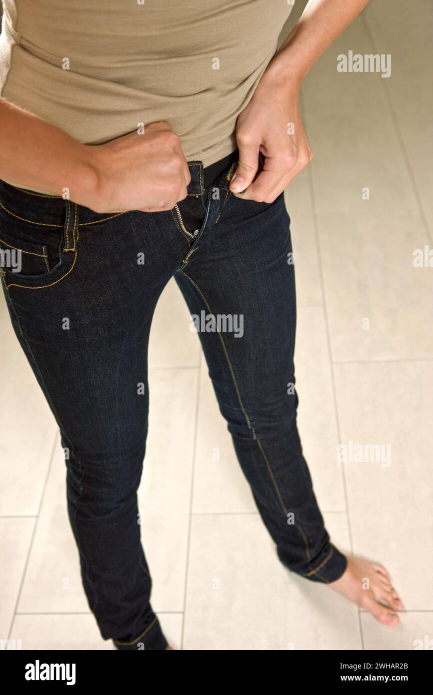 Woman buttoning very tight jeans Stock Photo