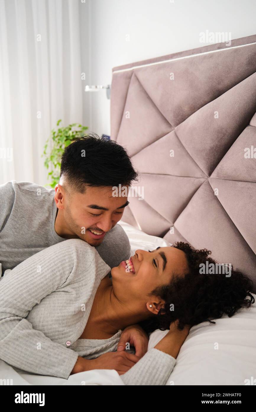 Multiethnic romantic couple wake up together in bed during honeymoon. Stock Photo