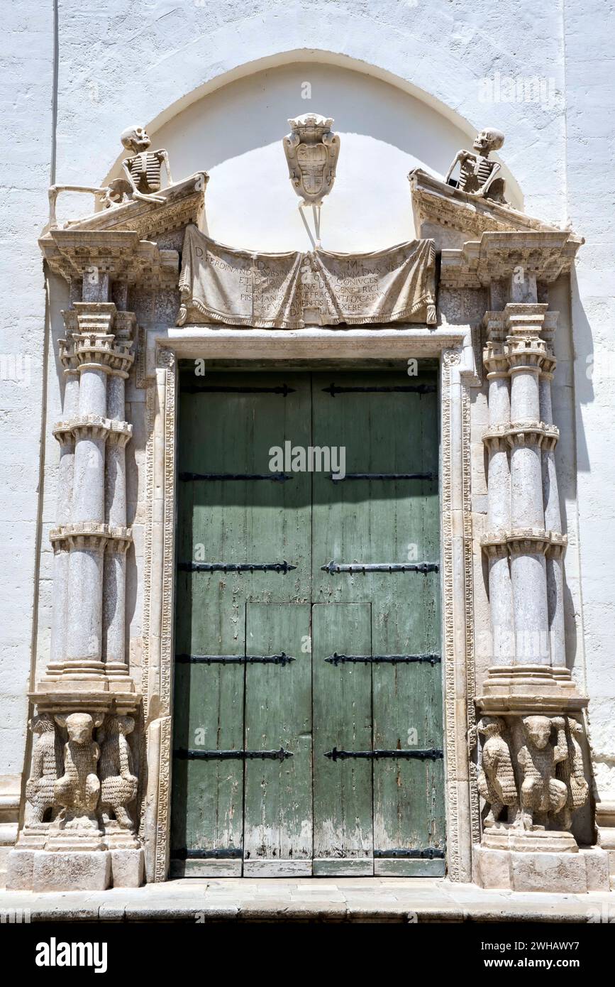 Portal of the Church of Purgatory (Santa Maria del Suffragio) in Gravina in Puglia. A triangular pediment is interrupted with two elongated skeletons. Stock Photo