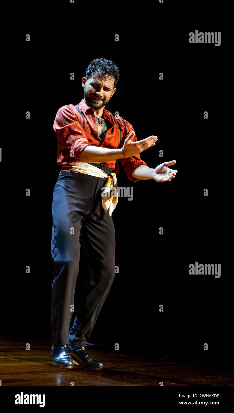 Captivating male flamenco dancer in colorful stage costume exudes emotion during a live performance, vertical photo. Stock Photo