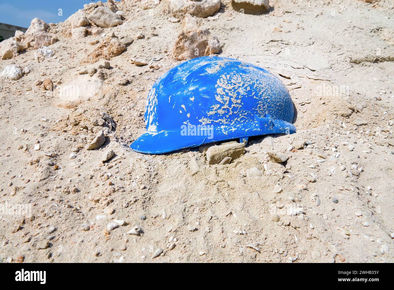Hastily abandoned construction helmet in the sand. Soil collapse natural disasters and catastrophes Stock Photo