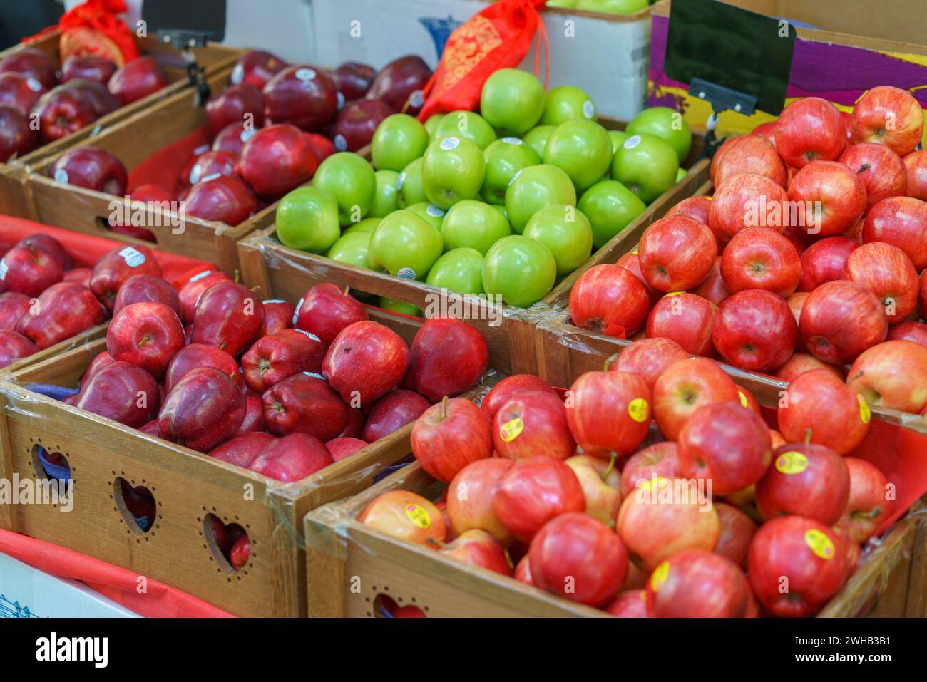 Wooden crates filled with a variety of fresh red and green apples on display at a local farmers market, showcasing organic and healthy produce Stock Photo