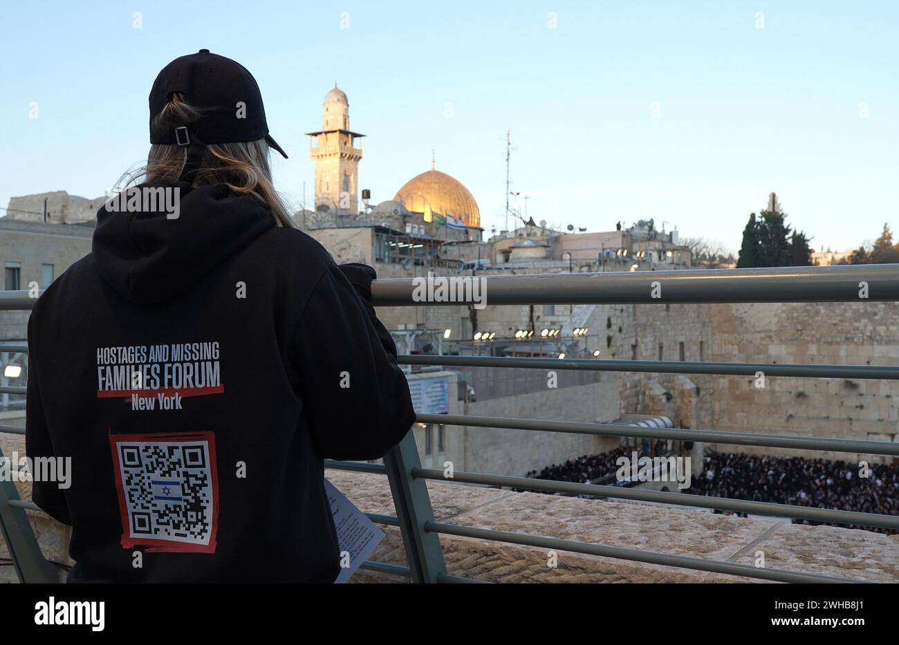 A supporter of the Hostage and Missing Families Forum which is volunteer organization based and laser-focused on bringing the Israeli hostages held in Gaza back home to their families, looks at the temple mount as Ultra-Orthodox Jews gather for a special prayer rally in the Western Wall, pleading for Israel's salvation, the release of hostages, and the safety of soldiers, amidst conflict in the north and south of the country on February 8, 2024 in Jerusalem Israel Stock Photo