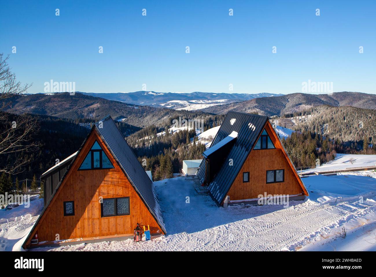 Two cozy houses covered in snow, nestled at the foot of majestic ...