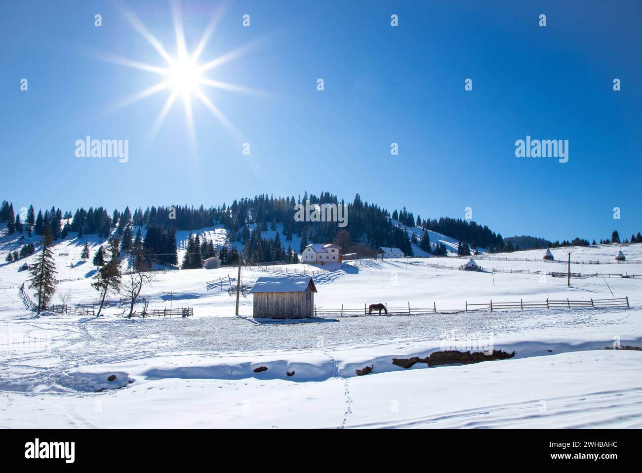 Sunrise over snowy mountain landscape with mountains in the background and a house in the foreground Stock Photo