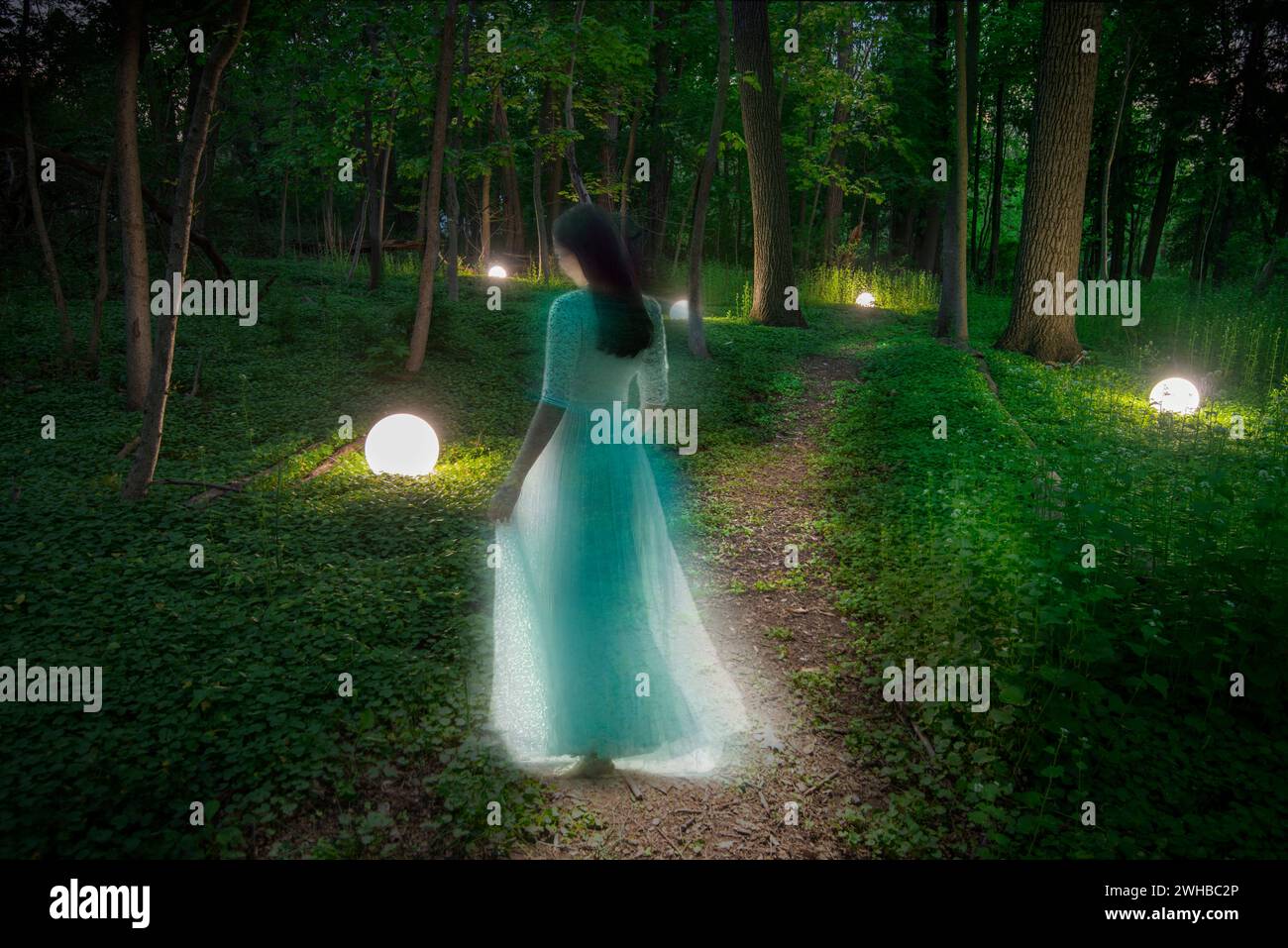 Woman in enchanted mythical forest with glowing orbs Stock Photo