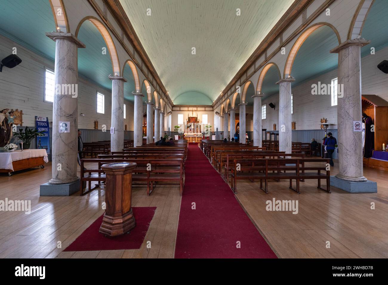 Interior view of an old wooden church on Chiloe including a white portico, round arches and red carpet. Stock Photo